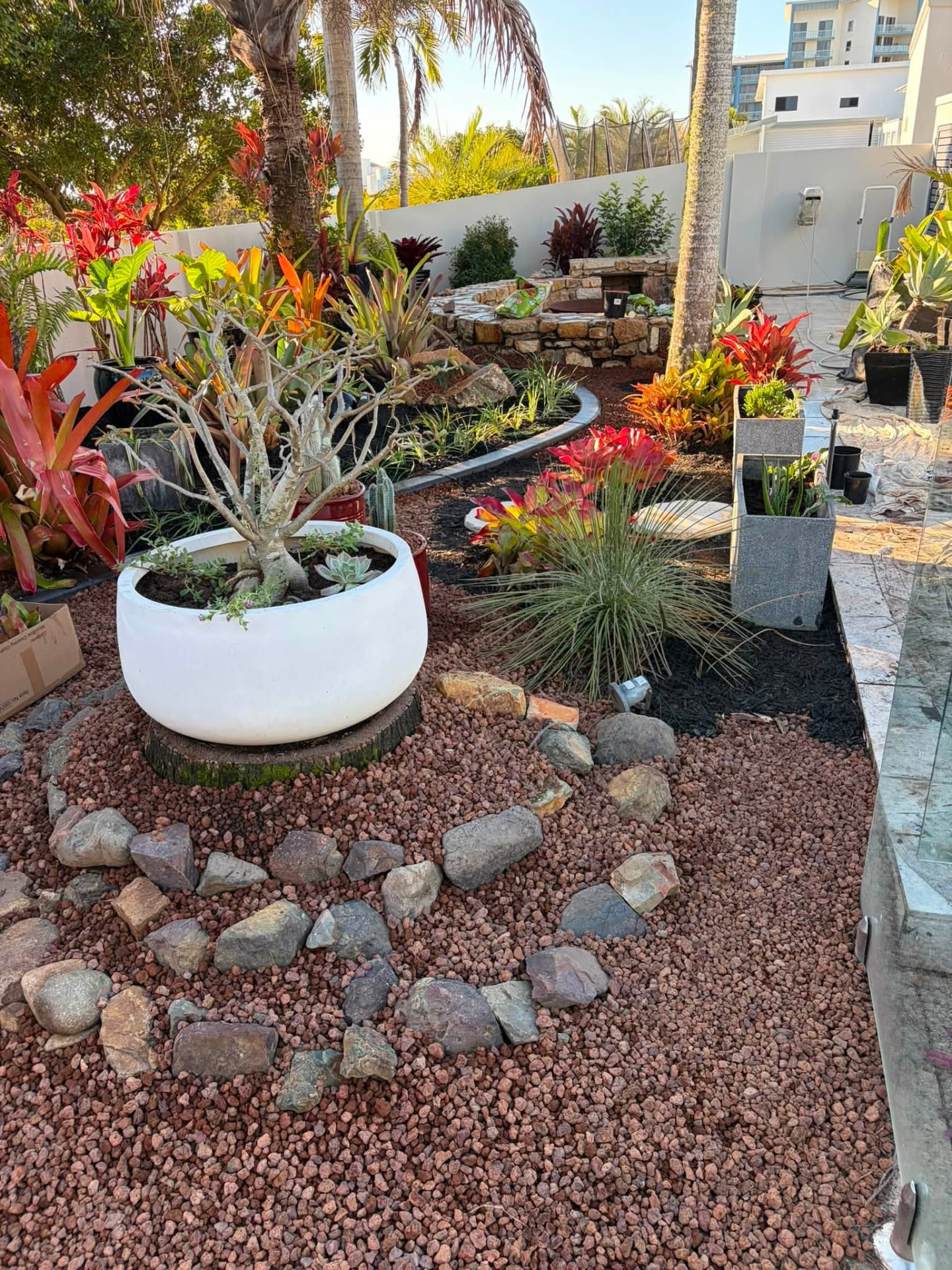 Designed tropical garden with feature pots, decorative rock and a stone fire pit